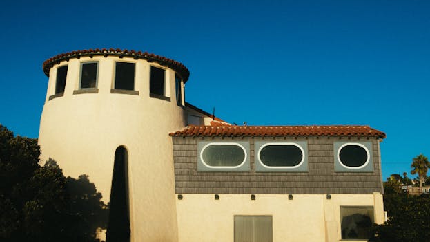 A striking residential building with round and rectangular windows under a vibrant blue sky.